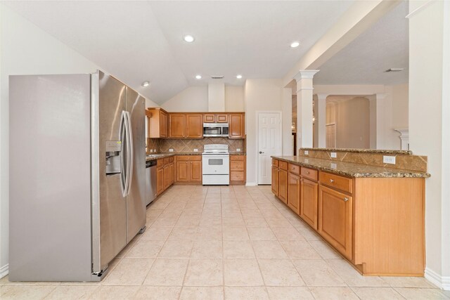 kitchen with dark stone countertops, stainless steel appliances, decorative backsplash, lofted ceiling, and ornate columns