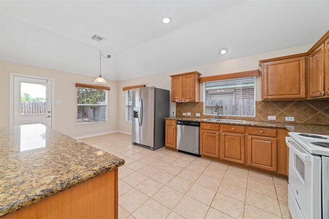 kitchen featuring visible vents, brown cabinets, a sink, stainless steel appliances, and vaulted ceiling