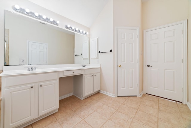 bathroom featuring double vanity, a sink, baseboards, and vaulted ceiling