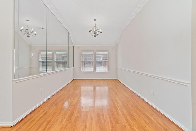spare room featuring wood finished floors, lofted ceiling, a chandelier, and ornamental molding