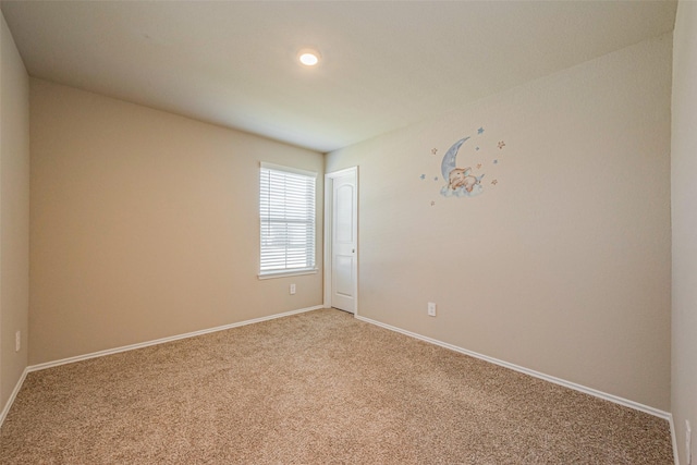 spare room featuring light carpet and baseboards