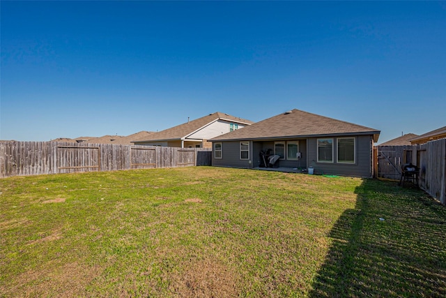 rear view of house with a lawn and a fenced backyard