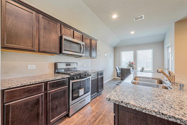 kitchen with wood finished floors, visible vents, a sink, stainless steel appliances, and dark brown cabinetry