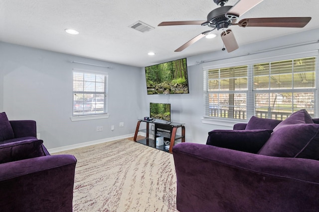 living room featuring baseboards, visible vents, recessed lighting, ceiling fan, and a textured ceiling