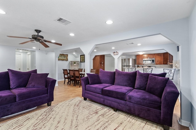 living room featuring visible vents, baseboards, light wood-type flooring, recessed lighting, and a ceiling fan