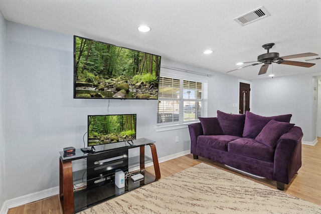 living area with wood finished floors, visible vents, and baseboards