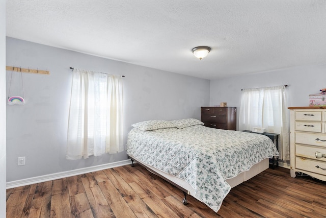 bedroom featuring dark wood finished floors, a textured ceiling, and baseboards