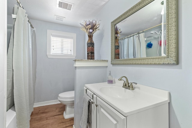 bathroom featuring vanity, a shower with shower curtain, wood finished floors, visible vents, and toilet