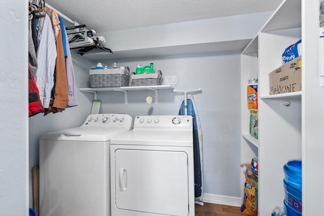 laundry area featuring baseboards, washing machine and dryer, laundry area, wood finished floors, and a textured ceiling