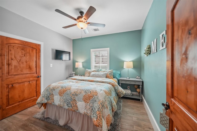 bedroom featuring visible vents, ceiling fan, baseboards, and wood finished floors