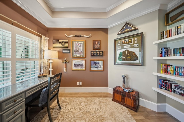 office space with crown molding, baseboards, a tray ceiling, built in desk, and wood finished floors