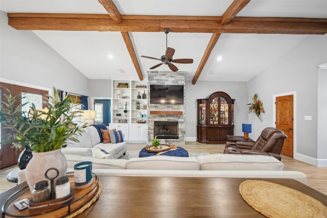 living area with a ceiling fan, baseboards, a stone fireplace, light wood-style floors, and beamed ceiling