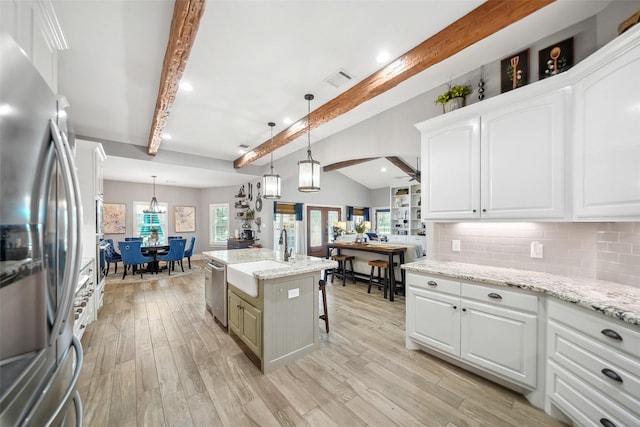 kitchen featuring lofted ceiling with beams, decorative backsplash, stainless steel appliances, light wood-style floors, and white cabinetry