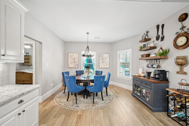 dining room featuring a notable chandelier, baseboards, and light wood finished floors