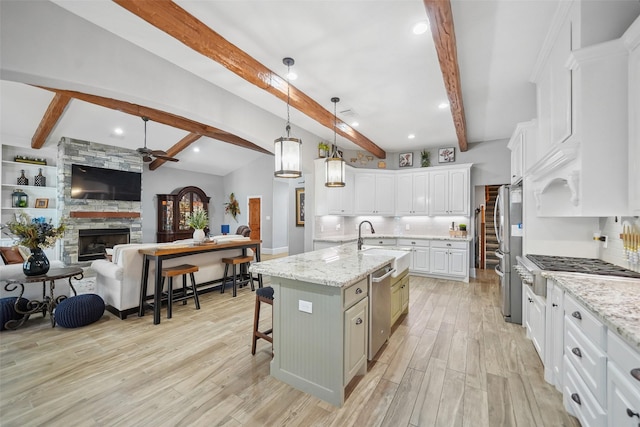 kitchen with light wood finished floors, a sink, stainless steel appliances, white cabinets, and open floor plan