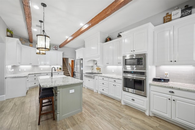 kitchen featuring tasteful backsplash, white cabinetry, stainless steel appliances, and light wood-style floors