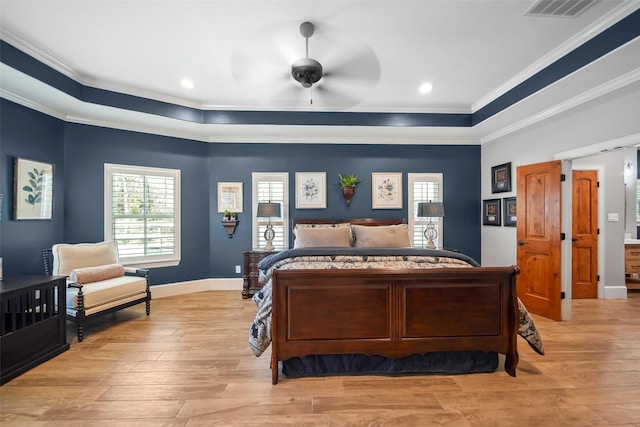 bedroom featuring light wood finished floors, visible vents, crown molding, baseboards, and a raised ceiling