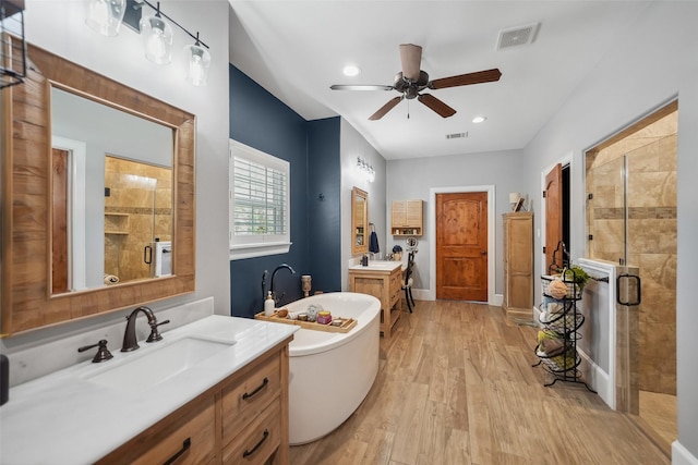 bathroom featuring a freestanding tub, visible vents, a stall shower, a sink, and wood finished floors