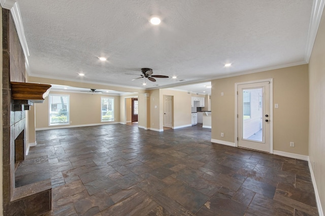 unfurnished living room with baseboards, a tiled fireplace, ornamental molding, stone tile flooring, and a textured ceiling