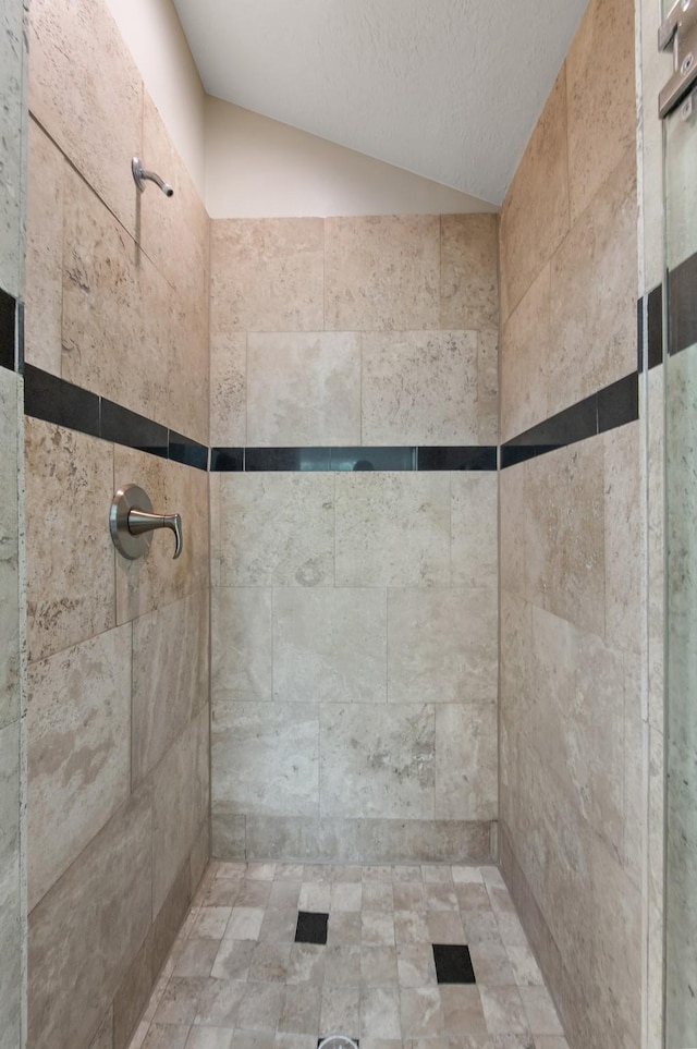 bathroom featuring tiled shower, a textured ceiling, and lofted ceiling