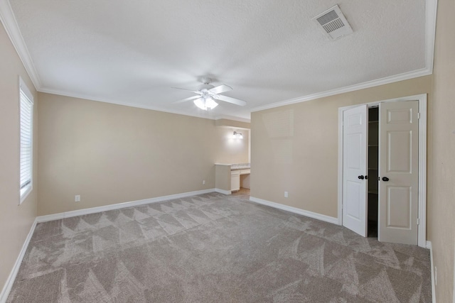 carpeted spare room featuring visible vents, crown molding, baseboards, a textured ceiling, and a ceiling fan