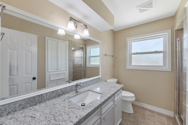 bathroom with visible vents, toilet, tiled shower, and baseboards