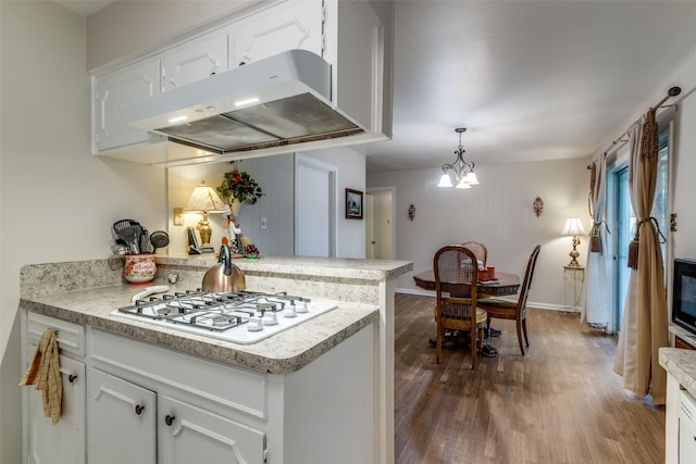 kitchen with white gas cooktop, under cabinet range hood, light countertops, a peninsula, and dark wood-style flooring