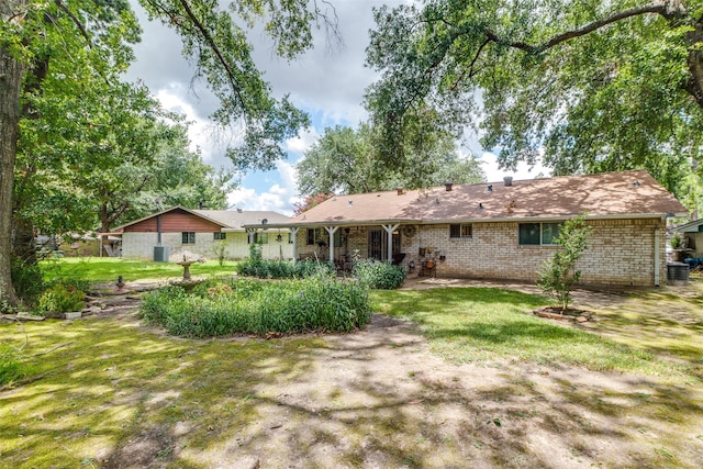 back of property with a yard and brick siding