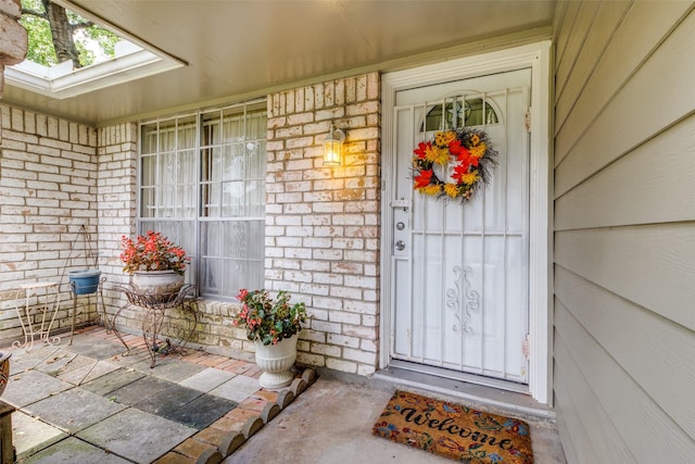 doorway to property with a porch and brick siding