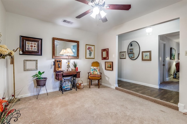 living area with visible vents, baseboards, a ceiling fan, and carpet flooring