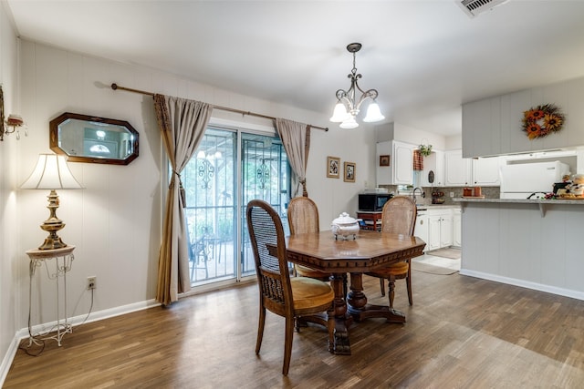 dining room featuring dark wood finished floors, a chandelier, baseboards, and visible vents