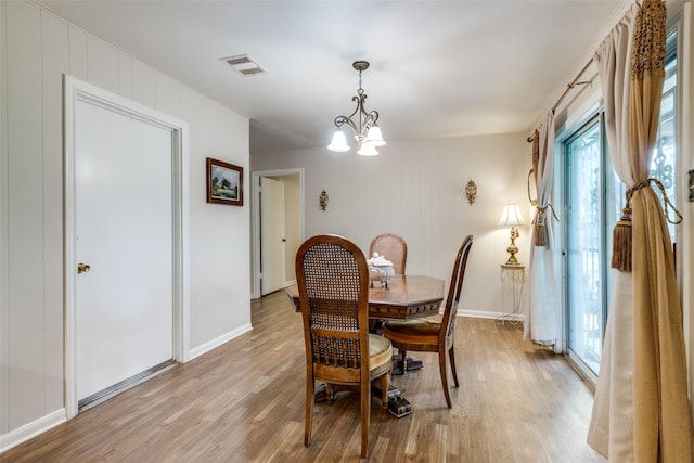 dining space featuring light wood-style flooring, a notable chandelier, baseboards, and visible vents