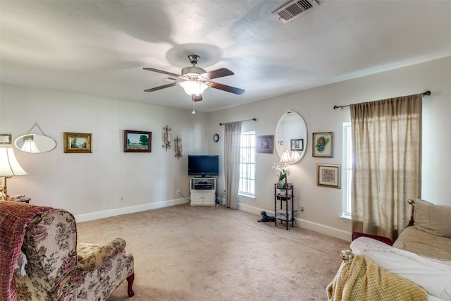 living room featuring baseboards, a ceiling fan, visible vents, and light carpet