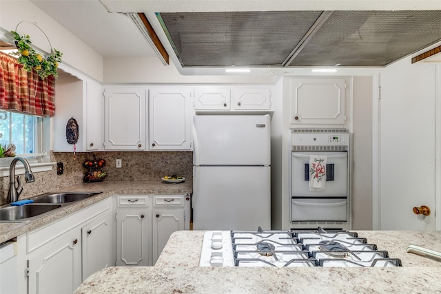 kitchen with a sink, white appliances, white cabinets, and light countertops