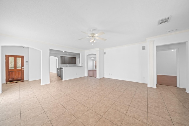 unfurnished living room with visible vents, ornamental molding, light tile patterned floors, arched walkways, and a ceiling fan