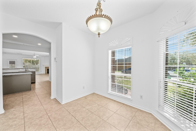 unfurnished dining area with light tile patterned floors, a healthy amount of sunlight, and a ceiling fan