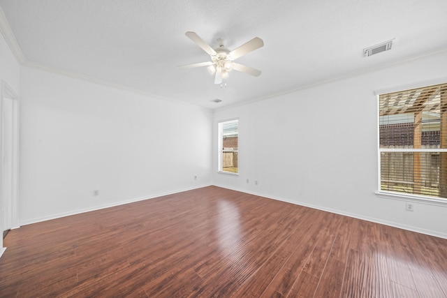 empty room with visible vents, baseboards, ceiling fan, ornamental molding, and wood finished floors