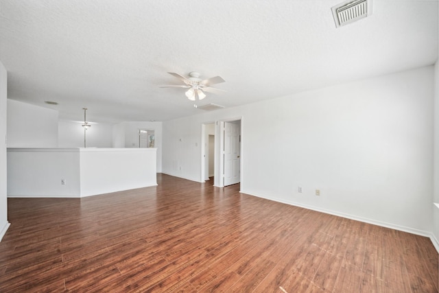 empty room featuring ceiling fan, visible vents, a textured ceiling, and wood finished floors