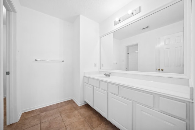 bathroom featuring tile patterned flooring, visible vents, walk in shower, baseboards, and vanity