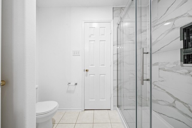 bathroom featuring tile patterned floors, a marble finish shower, and toilet