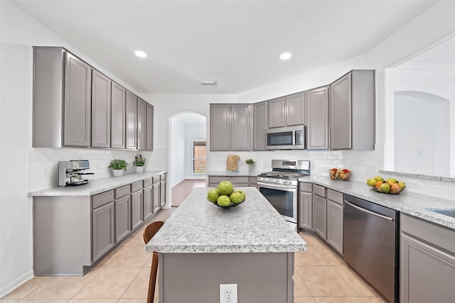 kitchen featuring visible vents, gray cabinetry, a kitchen island, appliances with stainless steel finishes, and light tile patterned flooring