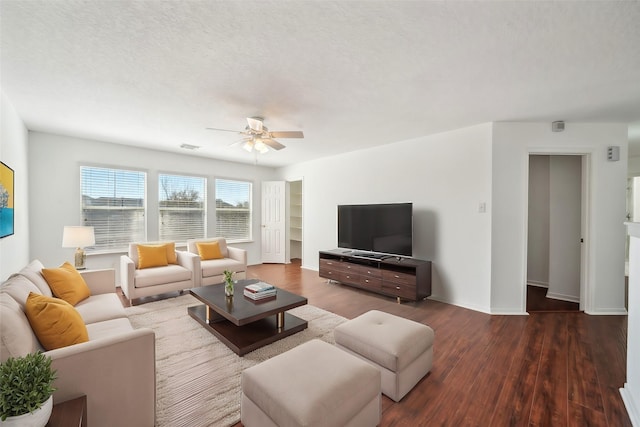 living area featuring visible vents, a textured ceiling, dark wood-style floors, baseboards, and ceiling fan