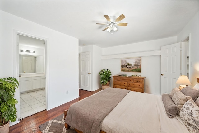 bedroom featuring a ceiling fan, ensuite bathroom, baseboards, and wood finished floors