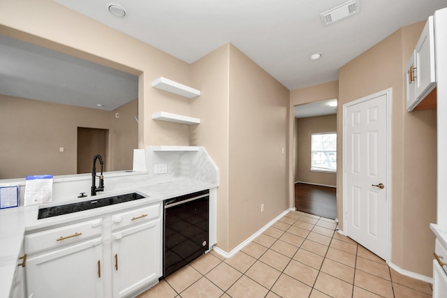 kitchen with light tile patterned floors, light countertops, black dishwasher, and a sink