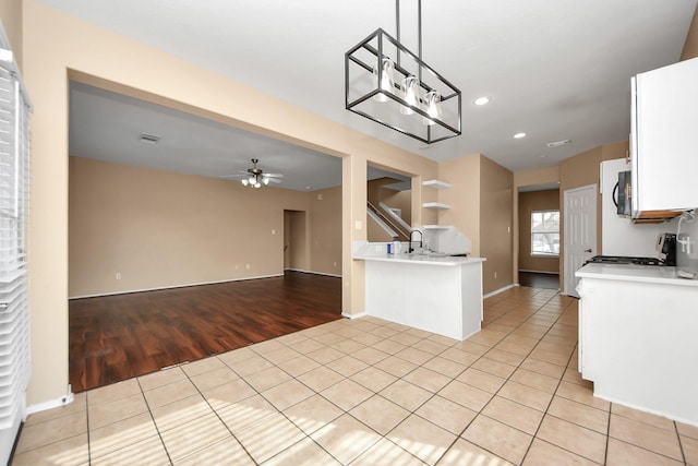 kitchen featuring stainless steel gas stove, open floor plan, white cabinetry, light tile patterned flooring, and light countertops