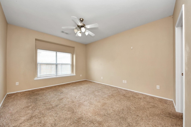 carpeted empty room with visible vents, baseboards, and a ceiling fan