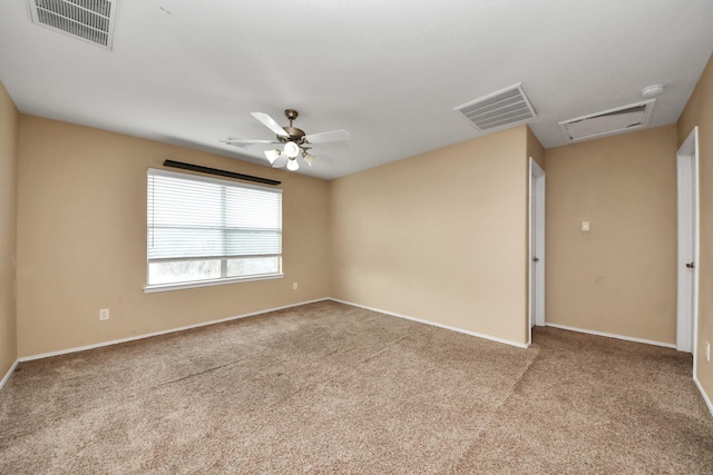 empty room featuring a ceiling fan, attic access, carpet, and visible vents