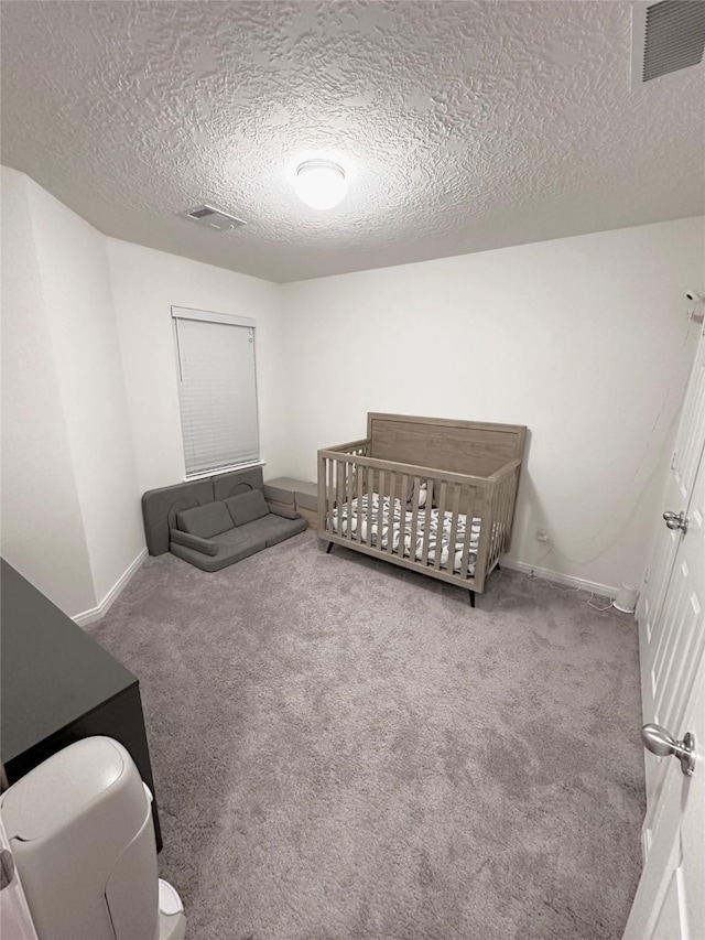 carpeted bedroom with visible vents, a textured ceiling, and baseboards