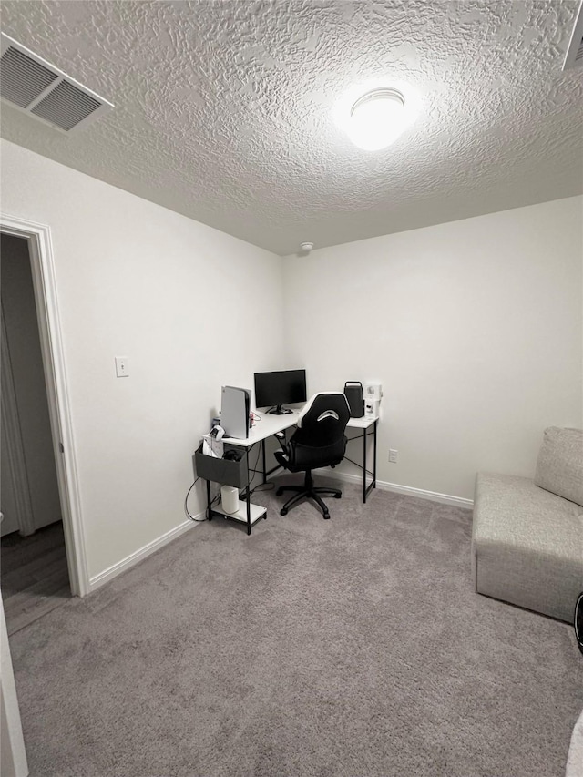 carpeted office featuring baseboards, visible vents, and a textured ceiling