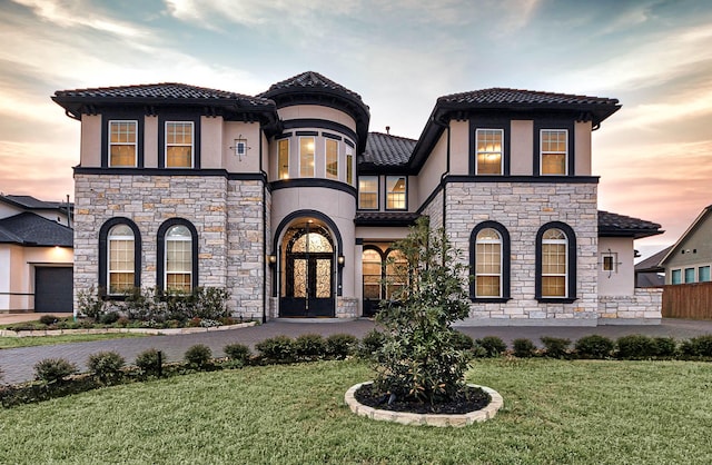 mediterranean / spanish home with stucco siding, a front yard, and driveway